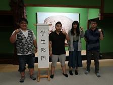 KG都市研究所・老舗応援隊の関係者4人が「学生部門」と書かれた紙のめくり台に立っている画像