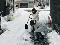 スコップをもって雪かきをする女性2名の写真