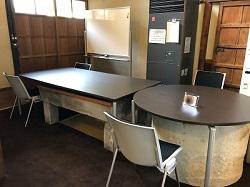 四角のテーブルと丸いテーブルが隣り合わせに置かれている打合せコーナーの写真