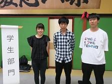 「学生部門」と書かれためくり台の横に立つ「石川工業高等専門学校豊島研究室」の関係者3名が並んでいる写真