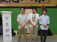 「学生部門」と書かれためくり台の横に立つ「KGチーム・MACHIYA」の関係者3名が並んでいる写真