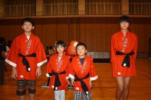 赤い法被を着て並んでいる子供4人の写真