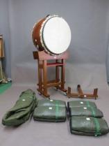 四本柱台に乗せられた平太鼓と、その周りに伏せ台や、太鼓用ケースが置かれている写真
