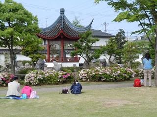蘇州市コーナーの付近にある芝生で人々が座ったりして眺めている様子の写真