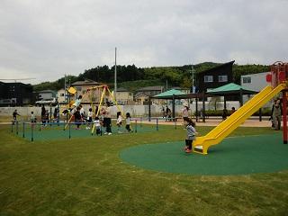 黄色いブランコや滑り台がありたくさんの子供たちが遊んでいる様子の写真