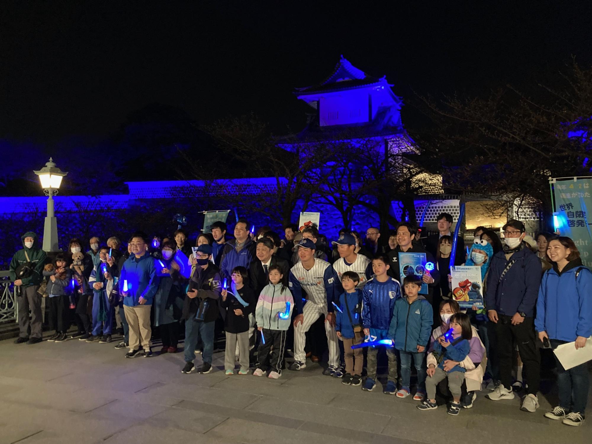 シンボルカラーの青でライトアップされた石川門の前での集合写真