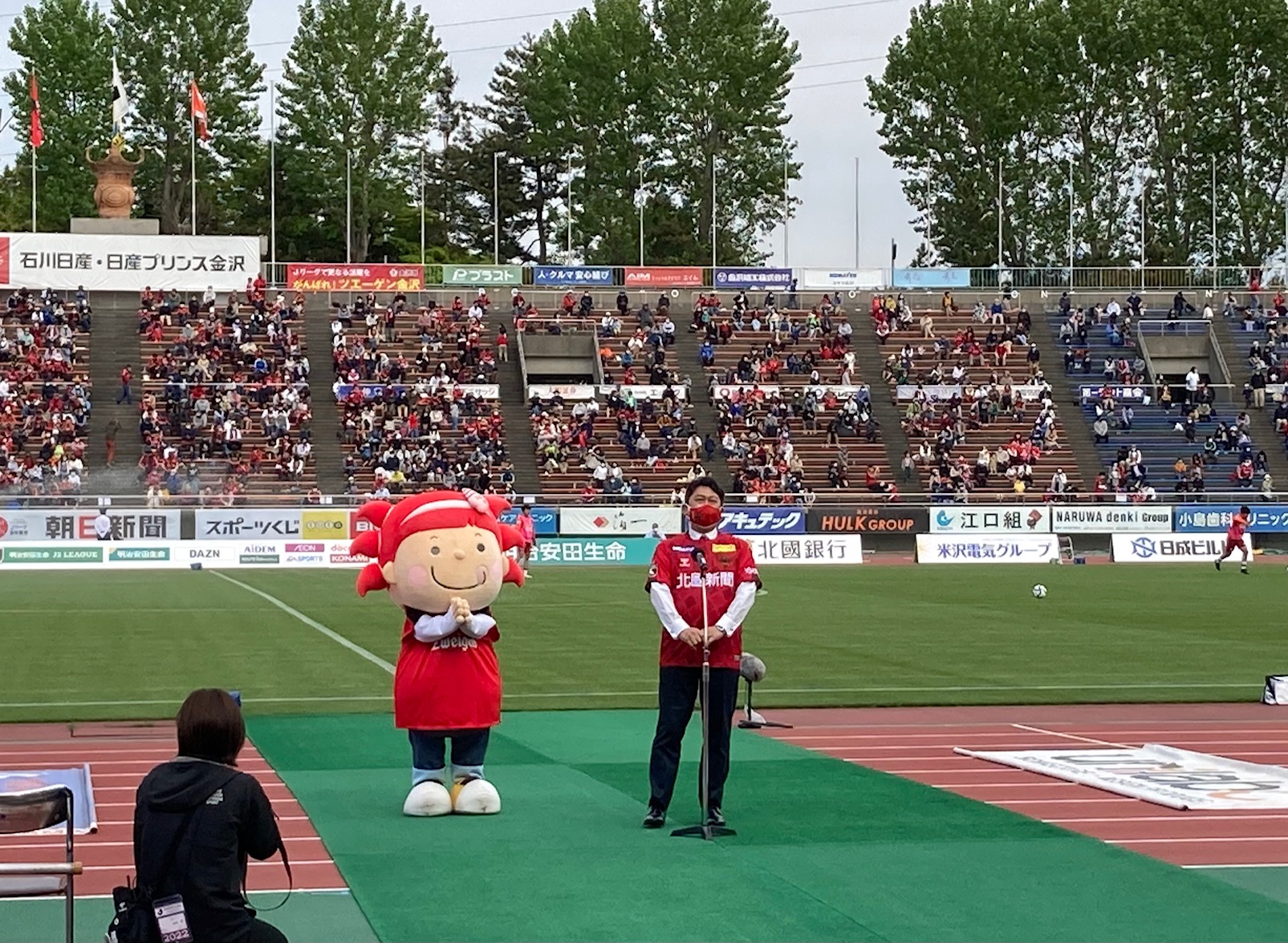 ツエーゲン金沢の試合でハーフタイムに挨拶をする村山市長とさかなざわさちこ
