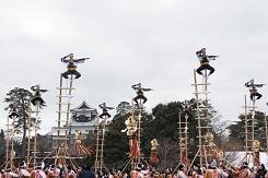 7つの長い梯子を縦にした上に消防団の人が一人ずつ乗って演技をしている出初式の様子を映した、ドキュメンタリー「金沢の宝物」の一場面の写真