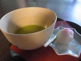 盆の上に置いた皿に和菓子が添えられ、左の茶碗にお抹茶が入っている写真