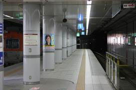ポスターが貼られている柱が並ぶ駅のホームの写真