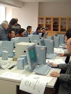 男女の高齢者がデスクトップ型の水色のパソコンを操作しているパソコンサロンのワンシーンを撮影した画像