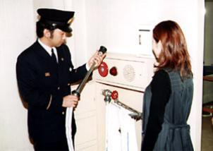 消火栓ホースの先を持ち、説明している指導員と話を聞く女性の写真