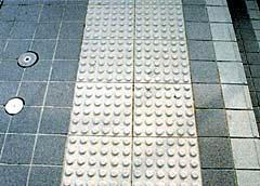 グレーのタイル状の地面に設置された点字ブロックの写真