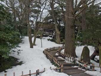 庭園の低い段がついた散策路の両側に、真っ白な雪に覆われた山崎山の写真