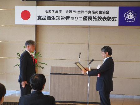 市長が表彰者と向かい合って賞状を渡そうとしている表彰式の写真