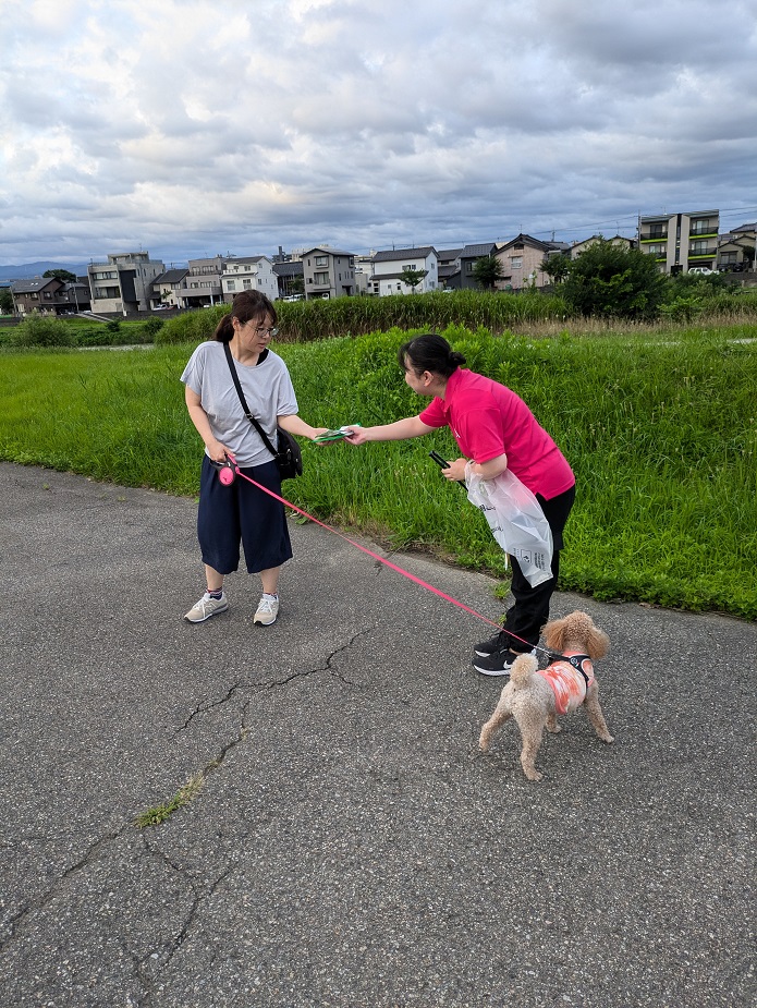 犬の飼い主にグッズを渡しながらマナー向上を呼びかけている写真