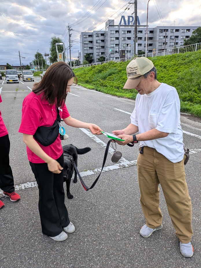 犬の飼い主にグッズを渡しながらマナー向上を呼びかけている写真