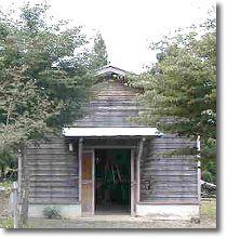 木に囲まれた木造の小屋の実習棟の写真