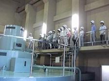 上寺津発電所の様子をヘルメットを被った参加者たちが見学している写真