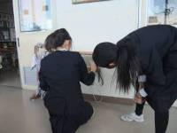 2人の女子生徒が壁の前で切電調査を行っている写真