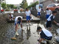 辰巳用水を子供たちがデッキブラシなどを使いながら掃除している写真