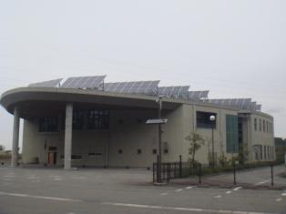 屋根には太陽光発電のパネルがついていて、手前が半円形の形になっている戸室リサイクルプラザの外観写真