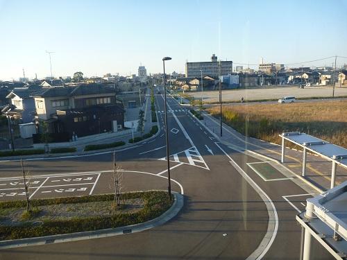 右側に田んぼ、左側に住宅が並んでいて、中央と左の手前に道路がある松島西金沢線の写真