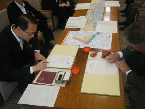 左側の席に座っている山野金沢市長が書類に記入をしている写真