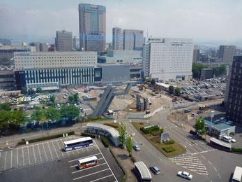 平成23年5月の工事進捗、北西から撮影した写真。駅前が整地され重機が停まっている。