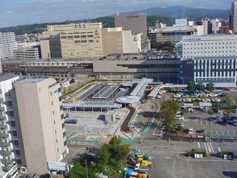 平成24年10月の工事進捗、北西から撮影した写真。奥の駐車場を囲むように緑の柵が立てられている。