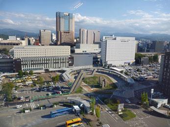 平成24年10月の工事進捗、北西から撮影した写真。緑の柵で囲まれた駐車場と工事が終わったバスロータリーが写っている。