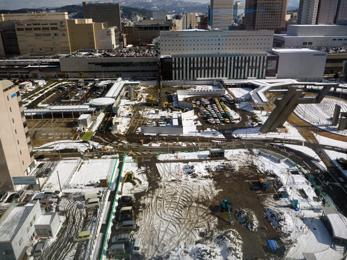 平成25年2月の工事進捗、北西から撮影した写真。一面が雪で覆われていて、手前の駐車場に重機が停まっている。