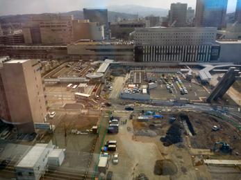 平成25年3月の工事進捗、北西から撮影した写真。手前の駐車場のアスファルトの地面がなくなり土が盛られている。