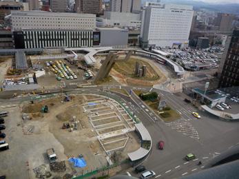 平成25年4月の工事進捗、北西から撮影した写真。手前の駐車場はトラックが停まりブルーシートが敷かれ工事が行われている。