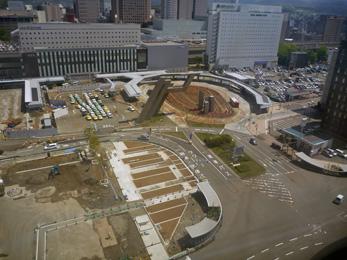 平成25年5月の工事進捗、北西から撮影した写真。手前の駐車場が整地され、中央付近にポールが立てられている。