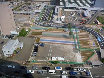 平成25年8月の工事進捗、北西から撮影した写真。手前の駐車場の奥側に長い青の線や茶色の線が塗られている。