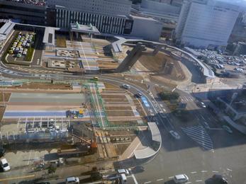 平成26年1月の工事進捗、北西から撮影した写真。手前の駐車場とタクシー乗降場の横側の地面に青と茶色の線が引かれている。