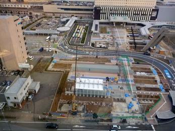 平成26年2月の工事進捗、北西から撮影した写真。手前の駐車場に白い屋根のついた建物が作られている。