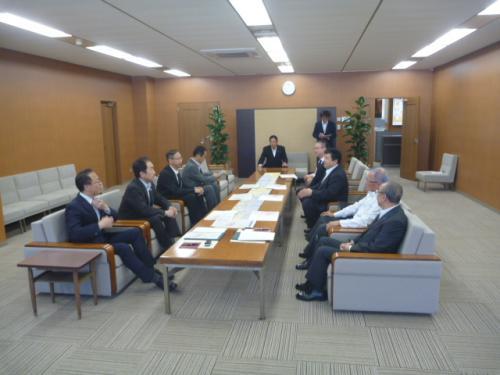 資料が置かれたテーブルの左側に市長を含む4名の男性、右側に4名の参加者が向き合って座っている写真