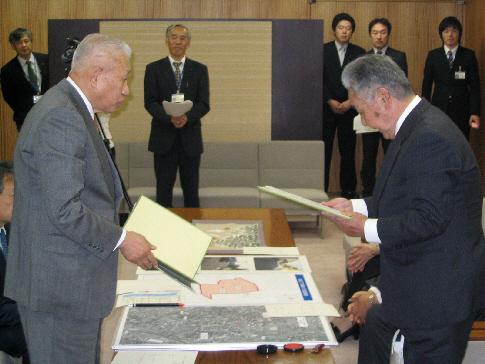 左側に山出金沢市長、右側に関係者の男性がそれぞれ協定書を持ち向かい合って立っている写真