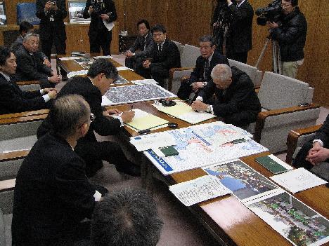 中央に置かれたテーブル右側に座っている市長と、左側に座っている男性がそれぞれの書類に記入をしている写真