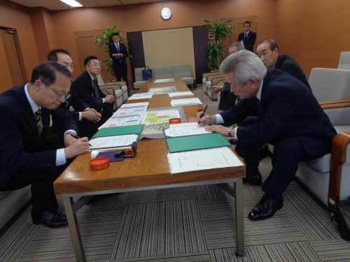 手前に座っている市長と長町交同会の関係者の男性がそれぞれの協定書に記入をしている写真