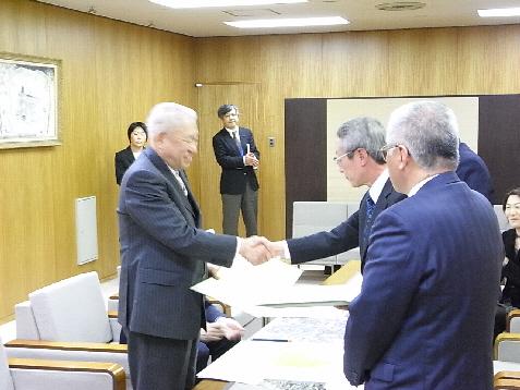 笑顔の山出金沢市長と関係者の男性が握手をしている写真