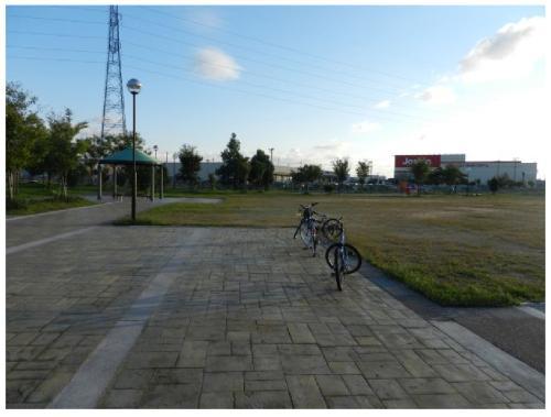 奥には芝生の広場、手前のアスファルトに自転車が2台停まっている松村あおぞら公園の写真