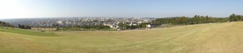 公園の丘の上から斜面になっている芝生、建物などの町の風景を撮影したパノラマの写真