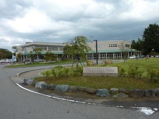 手前には石で囲まれ、木などが植えられた庭、奥に白い建物が立っている卯辰山健康交流センター千寿閣の外観写真