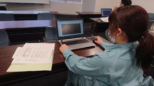 机の上に置かれたノートパソコンで作業をしている技術職員の写真