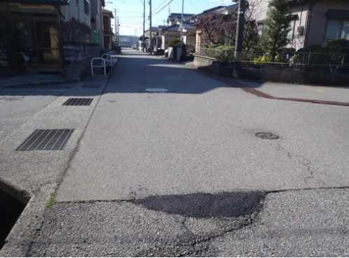 住宅街の中の道路のアスファルトに空いた穴を舗装した後の写真