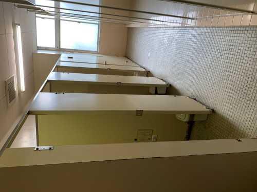 白い扉が並んでいるトイレの様子を横から写している改修前の写真
