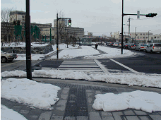 歩道の左右に雪が山積みになっていて、横断歩道の始まりに雪が堆雪している写真